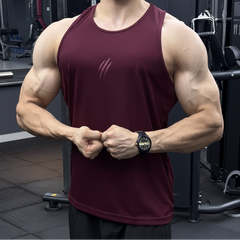 A muscular man in a gym wearing a sleeveless athletic tank top in deep burgundy with a small white claw-like logo on the chest. The background shows gym equipment.